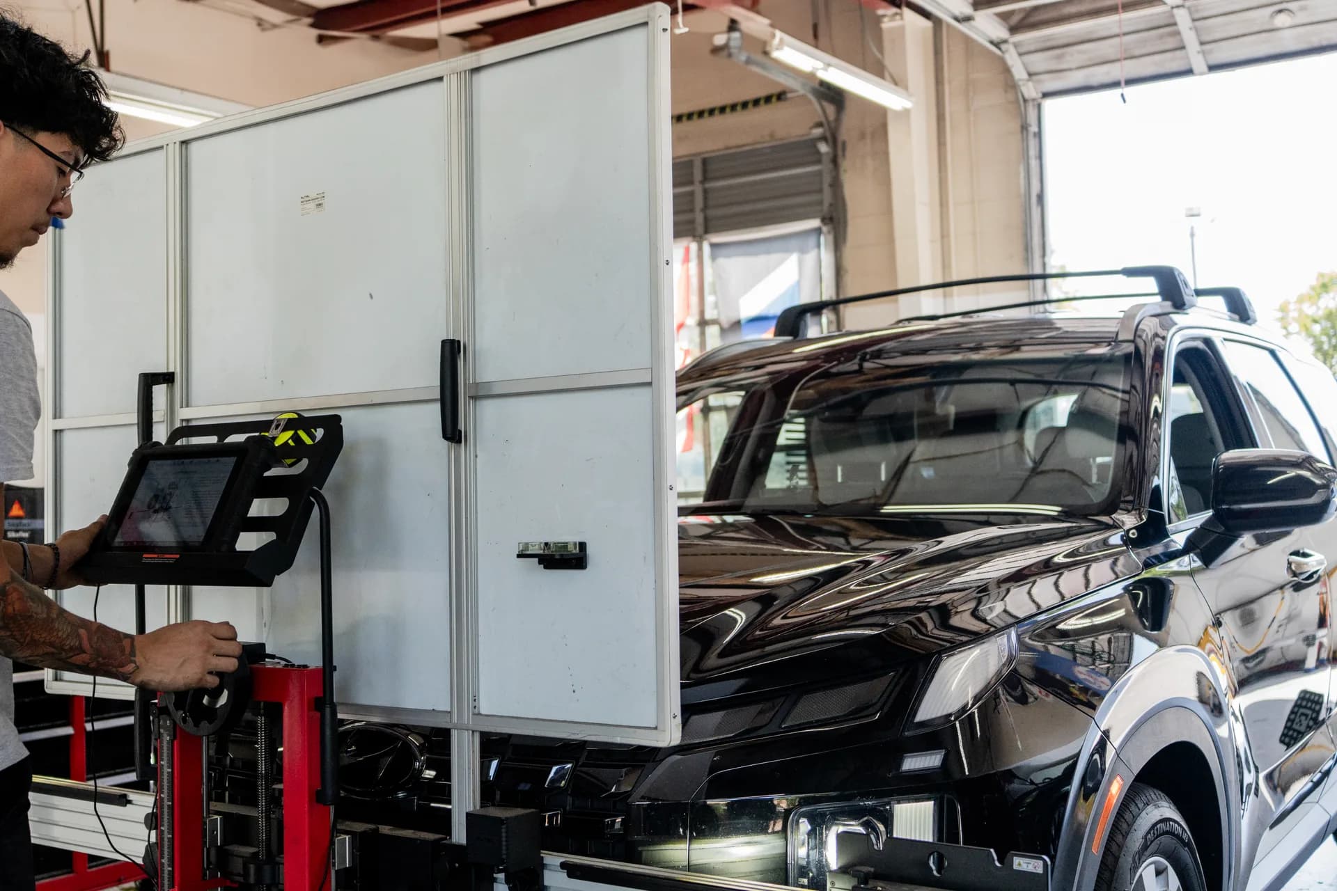 Technician using diagnostic equipment for ADAS calibration in the shop