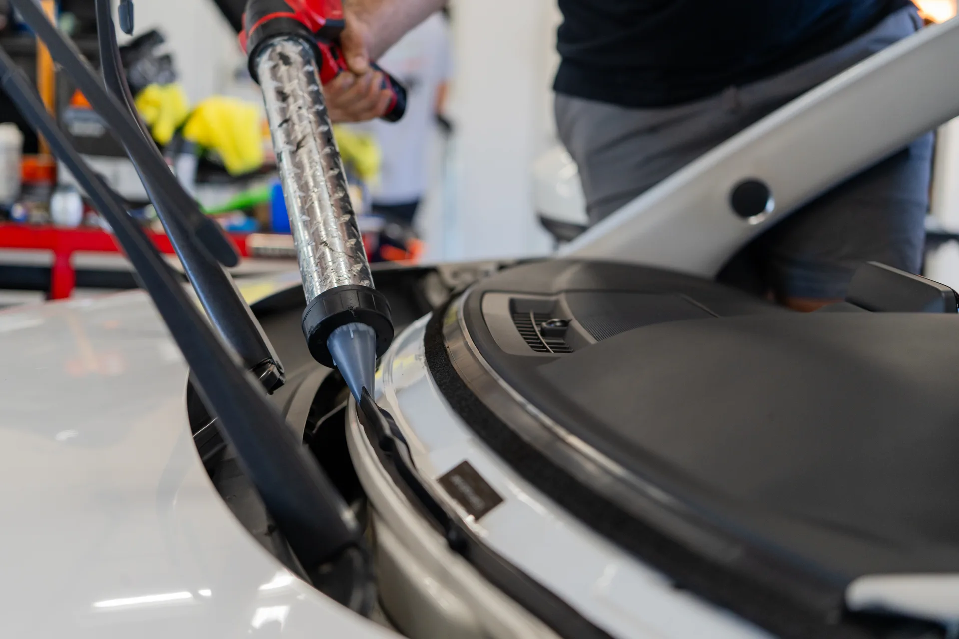Windshield repair tool positioned near the base of vehicle glass