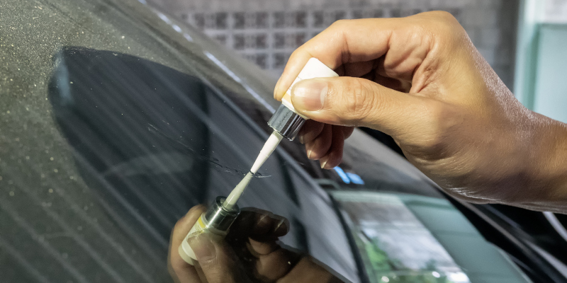 Man mechanic using glue welding cracked windscreen